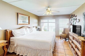 A bedroom with a bed, a ceiling fan, a television, and a desk with a chair. - Suntide II Condominiums #402 (South Padre Island)