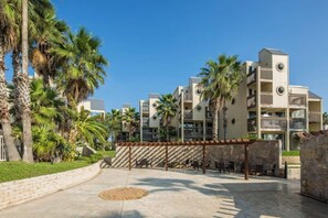 Ein Resort mit mehrstöckigen Gebäuden, Außenbereichen zum Sitzen und Palmen.