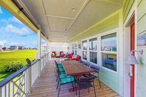 Ein überdachter Außenbereich mit Holzterrasse, Sitzgelegenheiten und großen Fenstern.