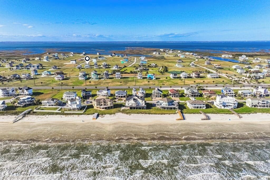 A coastal residential area with houses, a beach, and a clear view of the ocean.