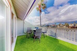 Ein Balkon mit Kunstgrasanlage, einem Tisch und Stühlen.