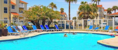 Una piscina con sillones de descanso y palmeras.