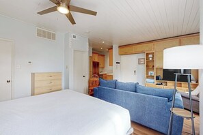 Ein Zimmer mit einem Bett, einem blauen Sofa, einer Stehlampe und einem Deckenventilator.