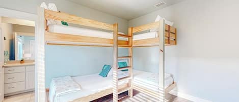 Habitación con literas, una escalera de madera, un escritorio pequeño y un espejo.