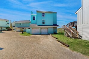 A residential area with houses featuring a similar architectural style, a driveway, and a grassy lawn. - Lost on the Sea | Lost Colony 3 - Gulf Views, Pool, Walk to Beach (Port Aransas)