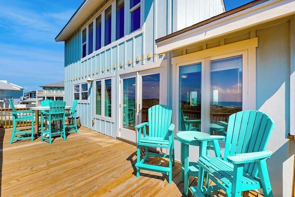A wooden deck with outdoor seating and large windows.