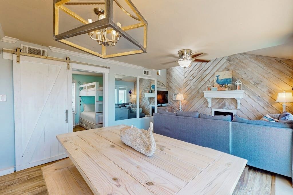 A modern living room with a wooden dining table, a sofa, and a fireplace.