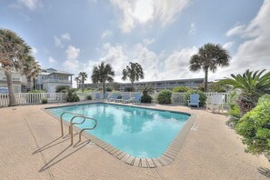 Ein Pool mit Liegestühlen und einer Holzterrasse, umgeben von Palmen.