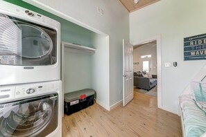 A laundry area with stacked washing machines and a storage bin. - Eskridge Gem Unit B - Near Shops & Beach, Dogs OK (Port Aransas)