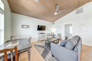 Un salon avec un plafond en bois, un ventilateur de plafond, une télévision, un canapé, une table basse et une table à manger avec des chaises.