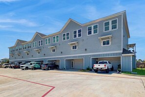 A multi-story residential building with several garage-style parking spaces. - Shoreline Retreat - Pool & Hot Tub, Walk to Beach (Port Aransas)