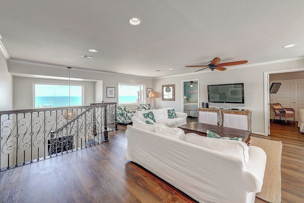 A spacious living area with a white sofa, a dining table, and a television.