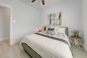 A bedroom with a bed, a nightstand, a lamp, and a painting on the wall. - LandsEnd - Indoor-Outdoor Living, Boat Parking (Rockport)