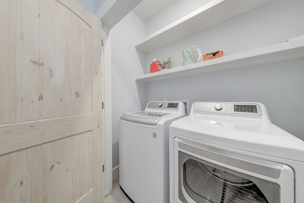 A laundry room with two front-loading washing machines and a wooden wardrobe.