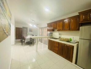 A kitchen with wooden cabinets, a white countertop, and a refrigerator. - Casa Moresca (Manzanillo)