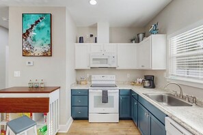 A modern kitchen with white cabinets, a built-in oven, and a microwave. - Three Palms By The Bay (Rockport)