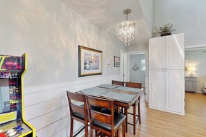 Ein Essbereich mit Tisch und Stühlen, einer Kronleuchter, einem Kühlschrank und einer Tür zu einem anderen Raum.