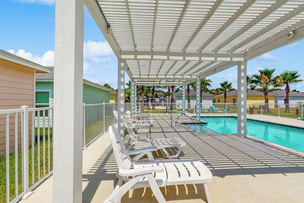 A covered pool area with lounge chairs and a pool.