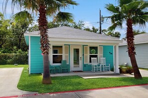 A small, single-story building with a teal exterior and a white roof. There are two palm trees in front of the building, and a red curb indicating a no parking fire lane. - Rockport Rendezvous - Pool, Pond & Fire Pit (Rockport)