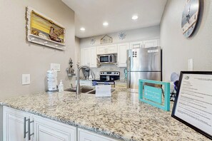 A kitchen with white cabinets, granite countertops, stainless steel appliances, and decorative wall art. - Belle of the Bay - Boat Slip, Pool & Tennis (Rockport)