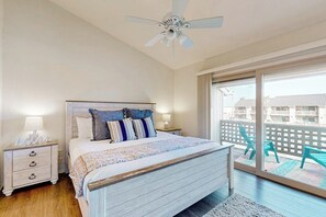 Una camera da letto con un letto, comodini, una ventola a soffitto e un balcone con sedie.