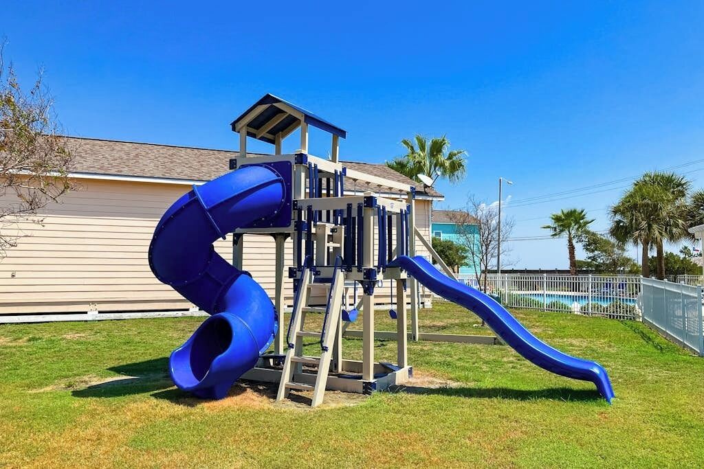 A playground with a blue slide and a climbing structure.