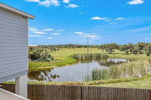 A residential property with a wooden fence, a pond, and a grassy field. - Barnacle Bay - Pool Access, Deck & EV Charger (Rockport)