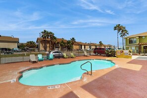 A swimming pool with lounge chairs and a no diving sign, surrounded by buildings and palm trees. - Cay Getaway - Private Balcony & Shared Pool (Corpus Christi)