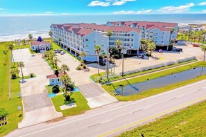 A hotel with multiple floors, a parking lot, and a view of the ocean. - Seascape #2319 Beach Happy (Galveston)