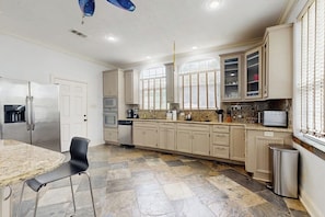 Una cocina con encimera de granito, electrodomésticos de acero inoxidable y armarios color beige.