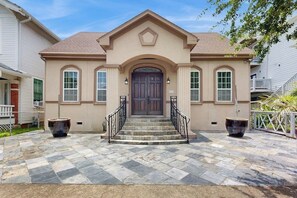 A two-story house with a central entrance, stone steps, and two large planters. - Sandcastle Retreat - Heart of Galveston, Dogs OK (Galveston)