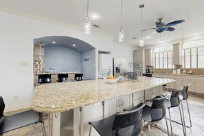 A kitchen with a large island, bar stools, and modern appliances. - Sandcastle Retreat - Heart of Galveston, Dogs OK (Galveston)