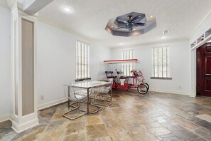 A spacious room with a dining table, chairs, a ceiling fan, and a bicycle. - Sandcastle Retreat - Heart of Galveston, Dogs OK (Galveston)