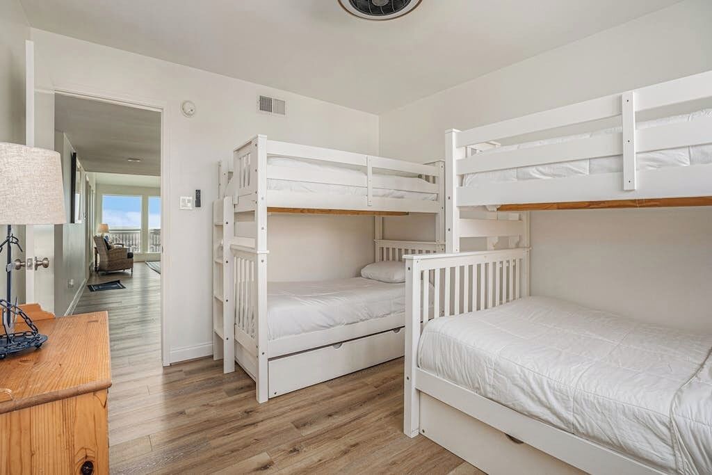 Um quarto com beliches, uma escrivaninha de madeira e uma luminária.