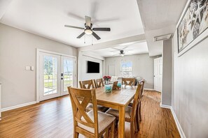 A dining area with a wooden table and chairs, a ceiling fan, and a view of the outdoors. - Redicare Resort - Entire Property (Galveston)
