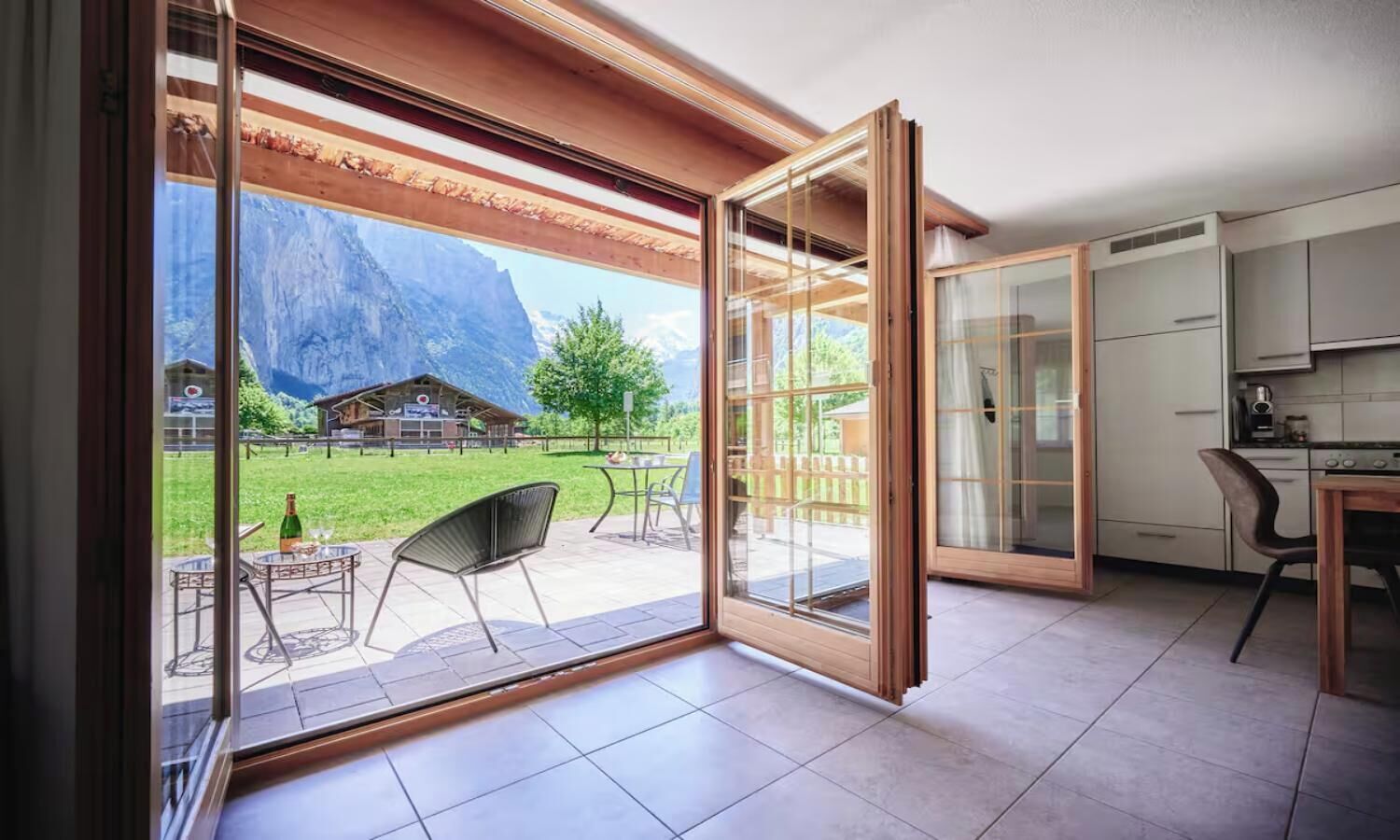 A modern kitchen with a dining area, a sliding glass door leading to an outdoor patio with a mountain view.