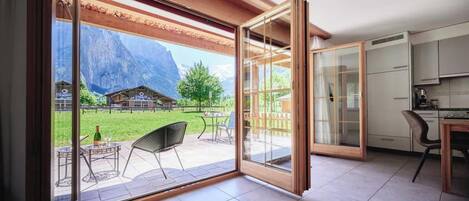 A modern kitchen with a dining area, a sliding glass door leading to an outdoor patio with a mountain view.