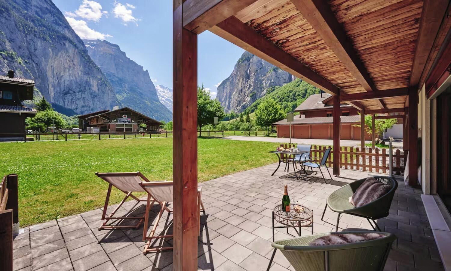 Une terrasse avec des meubles d’extérieur, une bouteille de champagne et une vue sur les montagnes.