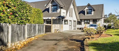 A residential area with two houses, a driveway, and a wooden fence.