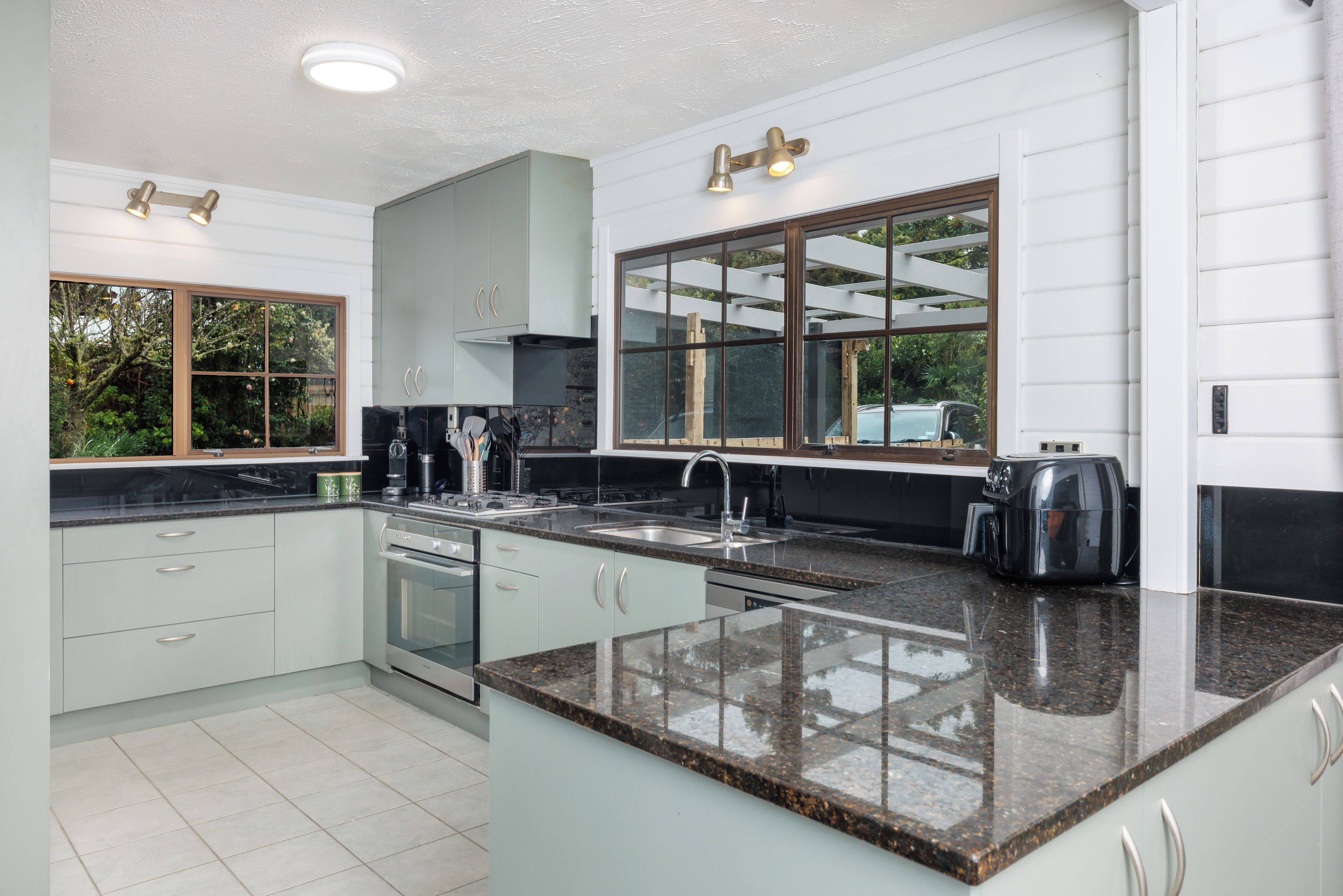 A modern kitchen with a granite countertop, stainless steel appliances, and a large window.