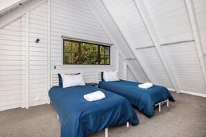 A room with two beds, a window, and a sloped ceiling.
