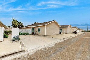 A row of single-story houses with attached garages, a clear sky, and a paved driveway. - Palm Bay 402 - Pool, Patio & Dog-Friendly (Corpus Christi)