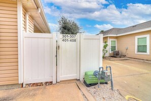 A gated residential area with a utility meter and a green container. - Palm Bay 402 - Pool, Patio & Dog-Friendly (Corpus Christi)