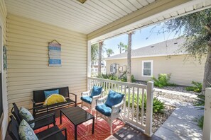 A covered porch with outdoor furniture, a white fence, and a view of a residential building. - Palm Bay 305 - Lagoon Pool, Patio & Dogs OK (Corpus Christi)