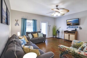 A living room with a sofa, a television, and a ceiling fan. - Palm Bay 305 - Lagoon Pool, Patio & Dogs OK (Corpus Christi)