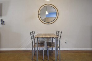 A dining area with a round mirror, a wooden table, and four chairs. - Palm Bay 305 - Lagoon Pool, Patio & Dogs OK (Corpus Christi)