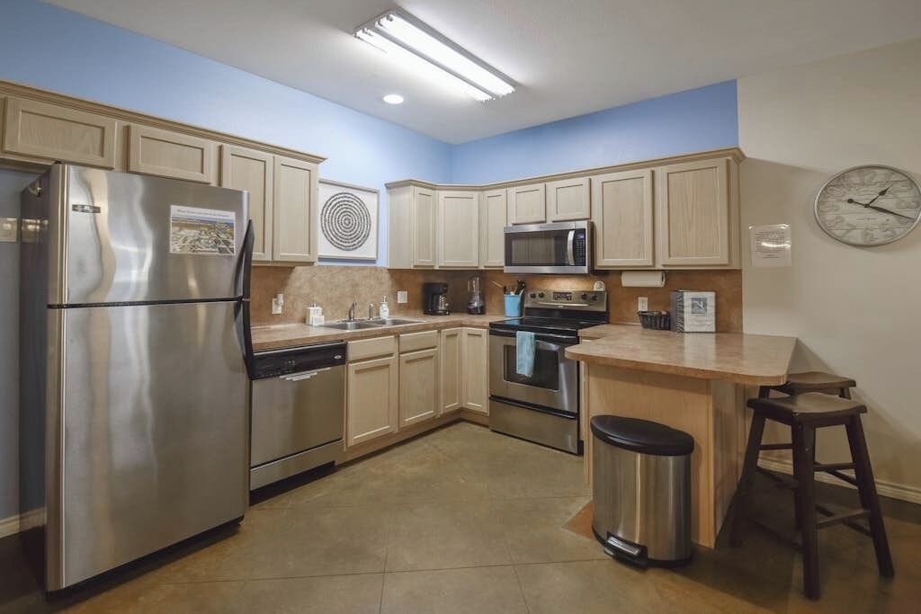 A modern kitchen with stainless steel appliances, wooden cabinets, and a blue accent wall.