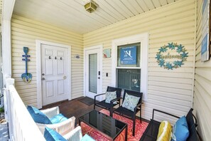 A covered porch with a glass table, two chairs, and a wicker sofa. - Palm Bay 305 - Lagoon Pool, Patio & Dogs OK (Corpus Christi)