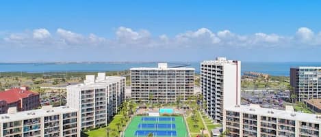 A hotel with multiple floors, a tennis court, and a pool area.