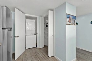 Une pièce avec un réfrigérateur, une porte blanche et un tableau accroché au mur.